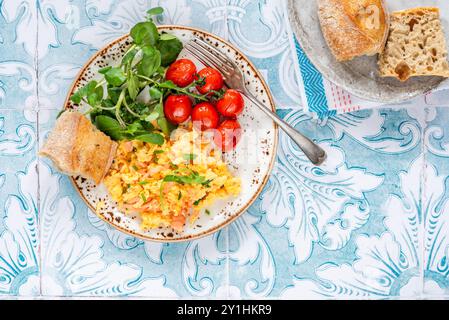 Rührei mit Räucherlachs, gerösteten Tomaten und knusprigem Brot Stockfoto