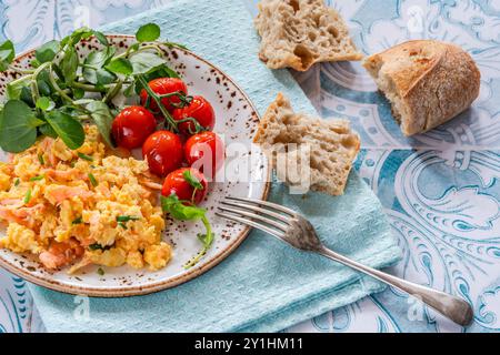 Rührei mit Räucherlachs, gerösteten Tomaten und knusprigem Brot Stockfoto