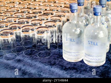 Ein Tischset mit zahlreichen klaren Gläsern und Flaschen stillem Wasser, gekennzeichnet mit „STILL“. Das Arrangement ist ordentlich und organisiert, passend für eine Veranstaltung Stockfoto