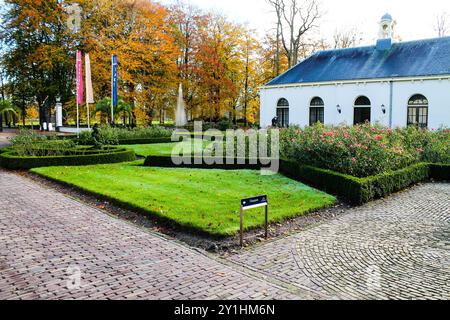 Ein gepflegter Garten mit ordentlich geschnittenen Hecken und lebendigen Blumenbeeten. Die Szene umfasst ein historisches Gebäude mit großen Fenstern, umgeben Stockfoto