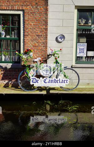 Delft, Niederlande - 19. Juni 2024; Delfter blaues Töpfergeschäft entlang des Kanals mit Fahrrädern, die mit blauer Keramik verziert sind, in Holland Stockfoto