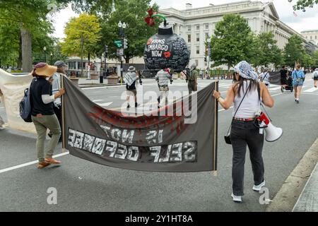 Washington DC, USA - 19.08.2024: Eine Gruppe von Demonstranten marschiert die Straße hinunter und hält ein Banner mit der Aufschrift „Völkermord ist keine Selbstverteidigung“. Stockfoto