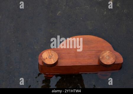 Ein hölzerner Spielzeugwagen kippte in einem See um und überflutet mit Wasser. Wird für Kfz-Versicherungen oder für Wasserschäden an Fahrzeugen verwendet. Stockfoto