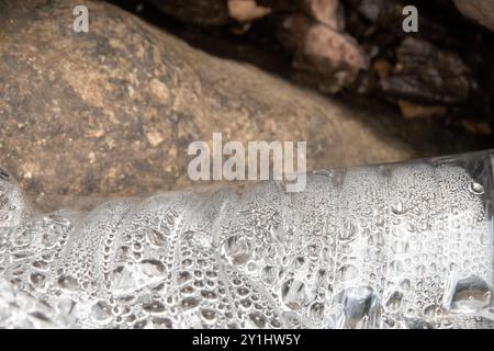 Nahaufnahme des Kondenswassers in einer Plastikflasche, die in den Felsen liegt. Müll, Müll ist schlecht für die Umwelt. Stockfoto