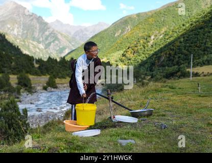 (240907) -- LHASA, 7. September 2024 (Xinhua) -- Konchog Rapten holt Wasser auf der Sommerweide in Nyangpo Township im Gongbo'Gyamda County, Nyingchi, südwestchinesische Autonome Region Xizang, 4. September 2024. Konchog Rapten ist ein 10-jähriger Junge, der in der fünften Klasse an der Central Primary School im Gongbo'Gyamda County, Nyingchi, studiert. Seine Schule, die auf einer Höhe von fast 4.000 Metern liegt, ist die höchste Schule im County. Die Schule ist gut ausgestattet mit modernen Einrichtungen, darunter Klassenzimmer mit interaktiven Touchscreen-Lernsystemen und Heizung. Der Campus ist auch fe Stockfoto