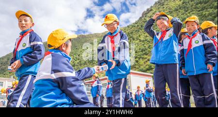 (240907) -- LHASA, 7. September 2024 (Xinhua) -- Schüler stellen sich an, um Milch an der zentralen Grundschule in Nyangpo Township im Gongbo'Gyamda County, Nyingchi, südwestchinesische Autonome Region Xizang, 4. September 2024 zu bekommen. Konchog Rapten ist ein 10-jähriger Junge, der in der fünften Klasse an der Central Primary School im Gongbo'Gyamda County, Nyingchi, studiert. Seine Schule, die auf einer Höhe von fast 4.000 Metern liegt, ist die höchste Schule im County. Die Schule ist gut ausgestattet mit modernen Einrichtungen, darunter Klassenzimmer mit interaktiven Touchscreen-Lernsystemen und Heizung. Der Campus Stockfoto