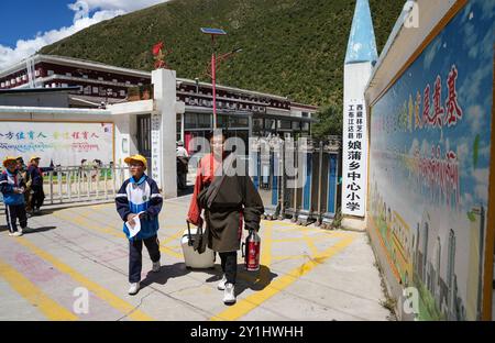 (240907) -- LHASA, 7. September 2024 (Xinhua) -- Wangden holt seinen Sohn Konchog Rapten (L) ab, um am Tor der Zentralschule in Nyangpo Township im Gongbo'Gyamda County, Nyingchi, südwestchinesische Autonome Region Xizang, am 4. September 2024 nach Hause zu gehen. Konchog Rapten ist ein 10-jähriger Junge, der in der fünften Klasse an der Central Primary School im Gongbo'Gyamda County, Nyingchi, studiert. Seine Schule, die auf einer Höhe von fast 4.000 Metern liegt, ist die höchste Schule im County. Die Schule ist gut ausgestattet mit modernen Einrichtungen, einschließlich Unterrichtsräumen mit interaktivem Touchscreen Stockfoto