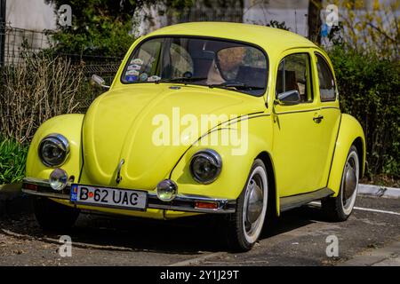 Bukarest, Rumänien, 2. April 2021 Alter gelber Volkswagen Beetle Oldtimer im Retro-Gelb parkte an einem sonnigen Frühlingstag eine Straße Stockfoto