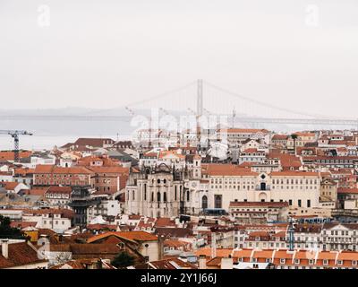 Blick aus der Vogelperspektive auf Lissabons historisches Zentrum mit roten Ziegeldächern, berühmten Wahrzeichen und der entfernten Hängebrücke vom 25. April über den Tejo. Stockfoto