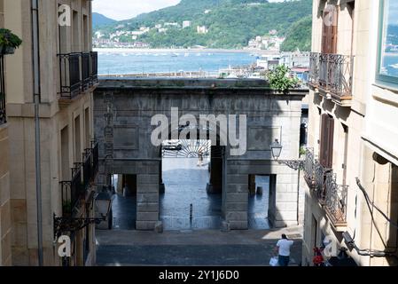 Blick auf die Docks durch einen Bogen in san sebastian, spanien. Sie können La Concha Strand mit Booten und Schiffen im blauen Wasser des Golfs sehen. Hinten Stockfoto