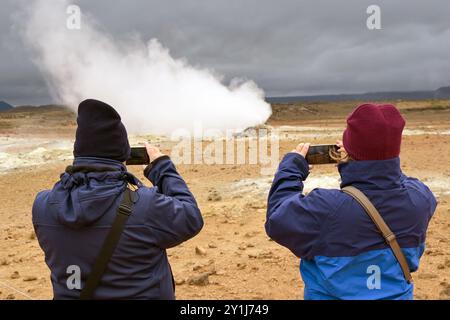 Hverir, Island - 24. August 2024: Touristen machen Fotos von einem dampfenden Fumarole an den heißen Quellen rund um das geothermische Gebiet von Hverir Stockfoto