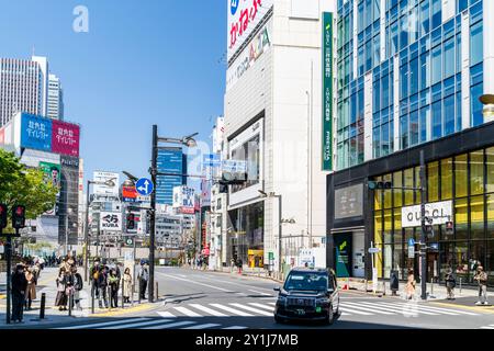 Blick auf die Shinjuku dori, Straße, an einem heißen Frühlingstag. Taxi überquert den Fußgängerübergang, während die Leute an der Ampel warten. Gucci Geschäft gegenüber. Stockfoto