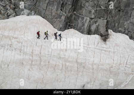 Chamonix, Frankreich - 22. August 2024: 4 Seilsteiger durchqueren ein vertikales Eisfeld unter einer Felswand auf dem Gletscher Mer de Glace in Chamonix, F Stockfoto