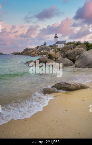 Der Leuchtturm von Pontusval, der sich an einem felsigen Punkt im Norden von Finistere in der Bretagne befindet, überblickt bei Sonnenaufgang ein Meer aus transparentem türkisfarbenem Wasser Stockfoto