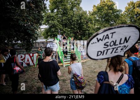 Berlin, Deutschland. September 2024. Teilnehmer einer Protestaktion während der Aktionswoche „Defence Görli“ überqueren symbolisch eine provisorische Holztreppe über eine Mauer im Görlitzer Park, um gegen die geplante Abzäunung des Görlitzer Parks zu protestieren. Quelle: Carsten Koall/dpa/Alamy Live News Stockfoto