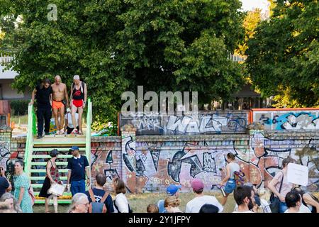 Berlin, Deutschland. September 2024. Teilnehmer einer Protestaktion während der Aktionswoche „Defence Görli“ überqueren symbolisch eine provisorische Holztreppe über eine Mauer im Görlitzer Park, um gegen die geplante Abzäunung des Görlitzer Parks zu protestieren. Quelle: Carsten Koall/dpa/Alamy Live News Stockfoto