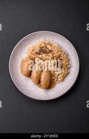 Fisch- oder Fleischquenelles mit Gemüse, Salz und Gewürzen in Pilzsauce auf dunklem Betonhintergrund Stockfoto