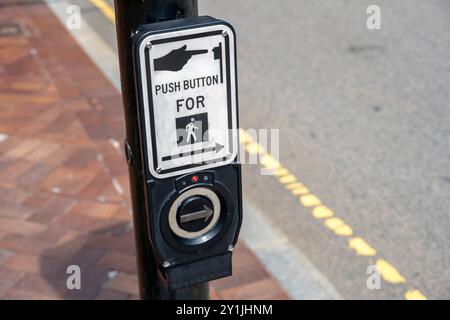 Fußgängerübergang Ruftaste zum Überqueren. Der Druckknopf am Lichtmast wird beim Überqueren eines Zebrakreuzes verwendet. Stockfoto