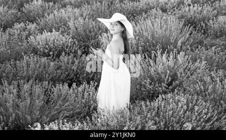 Fröhliches Teenager-Mädchen mit Lavendel auf dem Feld. Teenager mit Lavendelblume auf dem Feld. teenager mit Lavendel, der einen Blumenstrauß hält Stockfoto