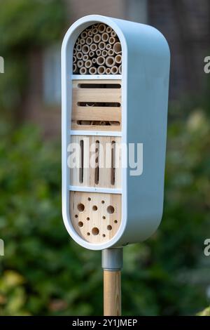 Modernes Insektenhotel an einer Stange in einem Garten mit Unterschlupf für Bienen, Schmetterlinge und weibliche Käfer. Stockfoto