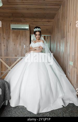 Elegantes Brautporträt im rustikalen Holzinnenraum mit atemberaubendem weißem Hochzeitskleid Stockfoto