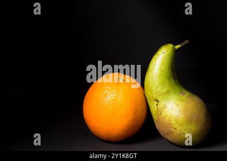 Stillleben einer Orange und einer Birne, Kunstbild mit schwarzem Hintergrund Stockfoto