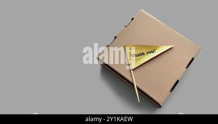 „Dankeschön“-Tag. Geschlossener quadratischer Karton mit winziger goldener Papierfahne. Schwarzer Text enthält „Danke!“ Stockfoto