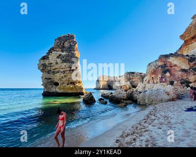 Junge Frau in Bikinis und seltsam geformten zerklüfteten Felsformationen und Klippen am Lagoa Beach, Faro District, Südportugal. Stockfoto