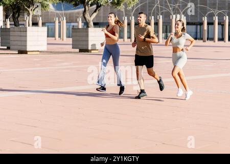 Drei junge Sportfreunde, die im Sommer gemeinsam im Freien joggen Stockfoto