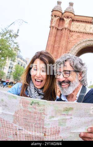 Aufgeregt kaukasische Paare mittleren Alters, die glücklich sind, sich die Karte in der europäischen Stadtstraße von Barcelona anzusehen Stockfoto