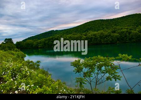 Untergehende Sonne reflektiert auf einem grünen See. Stockfoto