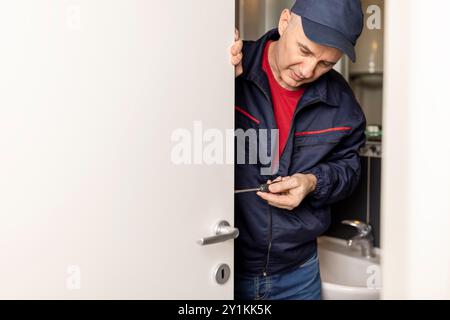 Reifer männlicher Handwerker Zimmermann, der an der Installation der Türverriegelung arbeitet Stockfoto