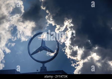 Symbolisches Bild, Dunkle Wolken bei Mercedes, Mercedes-Logo auf einem Gebäude umgeben von dramatischen Wolkenformationen und Lichtstrahlen am blauen Himmel, Stuttg Stockfoto