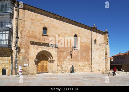 Eine einfache historische Kirche mit einer sandsteinfarbenen Fassade und großen Türen auf einem leeren Platz unter blauem Himmel, Kirche Santa Maria la Mayor, Soria Stockfoto