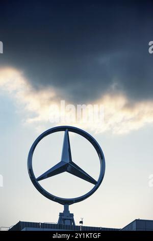 Symbolisches Bild, dunkle Wolken bei Mercedes, Mercedes-Benz Logo vor Sonnenuntergang mit Wolken über einem Industriebau, Stuttgart-Untertuerkheim Stockfoto