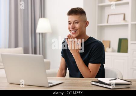 Junger Mann mit Gebärdensprache während Videogesprächen in Innenräumen Stockfoto