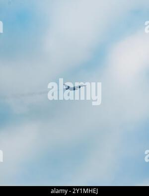 Aus der Vogelperspektive eines Kampfjets, der hoch über den wunderschönen Wolken fliegt und einen Kondensstreifen in einem klaren blauen Himmel hinterlässt. Stockfoto
