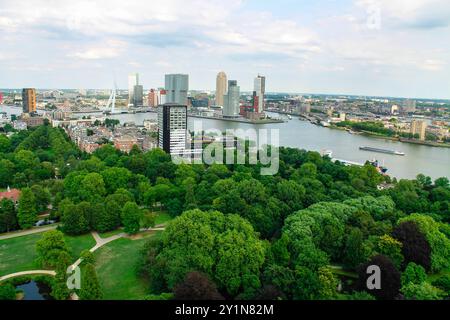 Ein Panoramablick auf die Skyline der Stadt mit modernen Wolkenkratzern entlang eines Flusses, umgeben von üppig grünen Bäumen und Parks. Die Szene fängt eine Mischung aus ein Stockfoto