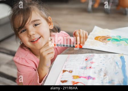 Fröhliches Kind, das sich zu Hause mit farbenfrohen Kunstprojekten beschäftigt Stockfoto