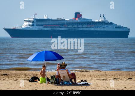 Cunard Kreuzfahrtlinie Queen Mary 2 nähert sich Liverpool auf dem Fluss Mersey, beobachtet von einer Familie, die am Crosby Beach sonnt. Stockfoto