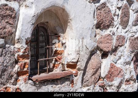 Kleines Fenster in der Steinmauer eines mittelalterlichen Gebäudes Stockfoto