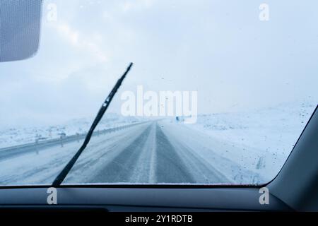 Straße mit vorübergehendem Schnee im Winter aus dem Inneren eines Autos gesehen ein Auto Stockfoto