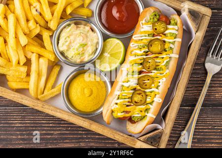 Köstliches Hot Dog Sandwich mit Saucen und Pommes Frites auf der Seite Stockfoto