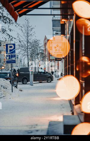 Minibus fährt auf verschneiten Winterstraßen hinter Bokeh in Rovaniemi, Lappland Stockfoto