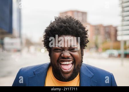 Glücklicher afrikanischer Mann in Übergröße, der draußen vor der Kamera lächelt – körperpositiv und Lifestyle-Konzept – Fokus auf das Gesicht Stockfoto