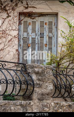 Alte blaue Fensterläden in einem alten griechischen mediterranen Gebäude mit Balkon und Geländer. Stockfoto