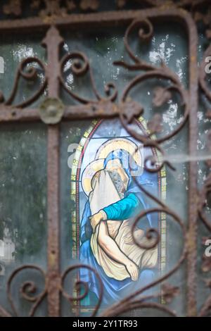 Buntglasfenster mit der Darstellung der Jungfrau Maria, die den Leichnam Christi in einem Mausoleum auf dem Friedhof Pere Lachaise in Paris, Frankreich, hält Stockfoto