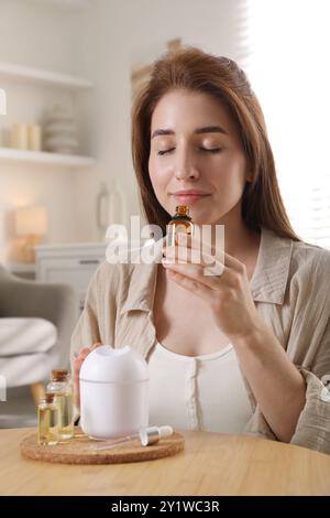 Frau mit Aromadiffusor und Flasche ätherischen Öls zu Hause Stockfoto