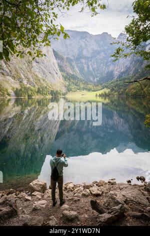 Vertikale Aufnahme eines Mannes, der am Ufer des noch schönen grünen Alpensees in Obersee fotografiert Stockfoto