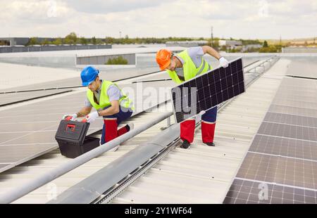 Zwei Ingenieure montieren ein Solarpanel auf dem Dach. Stockfoto